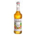 A close-up of a Monin Hawaiian Island Fruit Syrup bottle with a label.