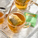 A glass cup of Twinings white tea with a bag in it on a saucer.