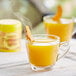 A glass cup of orange David Rio Turmeric Latte.