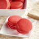 A white plate of red macarons.