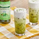 Two glasses of Monin Matcha Green Tea with a bottle of green liquid.