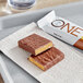 A tray of ONE S'mores Protein Bars with a chocolate bar next to a white wrapper.