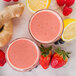 Two glasses of pink smoothie with strawberries, ginger and lemon next to Smartfruit Lemon Blush Puree.