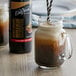 A glass jar filled with brown DaVinci Gourmet Iced Coffee Concentrate with a straw in it.