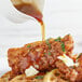 A plate of chicken and waffles being poured with Butternut Mountain Farm Grade A Dark Pure Vermont Maple Syrup.