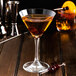 A martini glass with Fabbri Amarena Cherries on a wooden table.