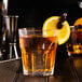 A glass of Fabbri Amarena cherries in a glass of whiskey with ice and a lemon slice.