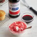 A cupcake with red frosting in a bowl next to a bottle of McCormick red food coloring.