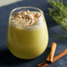 A yellow drink with whipped cream and cinnamon sticks next to DaVinci Gourmet Sugar Free Eggnog Flavoring Syrup.