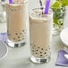 Two glasses of Fanale lavender bubble tea with purple straws on a white background.