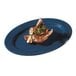 A Texas Blue oval platter with meat and vegetables on it.