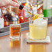 A hand using a dropper to add Bittercube Disco Inferno Tincture to a drink on a table.