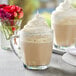 A glass mug of Capora vanilla latte/frappe mix with whipped cream on top.