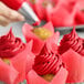 A close-up of a cupcake with red frosting on a brown surface.