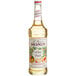 A bottle of Monin white peach syrup with a label.