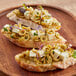 Slices of bread topped with Pitted Manzanilla olives and cheese on a wooden table.