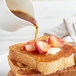 A plate of French toast with strawberries covered in Butternut Mountain Farm organic maple syrup.