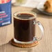 A glass mug of Lavazza Classico ground coffee on a table next to a bag of coffee.