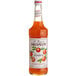 A bottle of Monin Premium Mandarin Fruit Syrup with orange liquid.