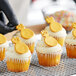 A cupcake with gold frosting and pineapple decorations.