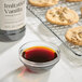A close up of a bottle of brown liquid vanilla next to cookies.