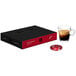 A black and red Nespresso Professional box of decaffeinated coffee capsules on a table with a glass of brown liquid.