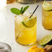 Two glasses of yellow drinks with lime and mint leaves on a table.