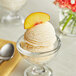A bowl of Lloyd's of Pennsylvania peach ice cream with a slice of peach on top.