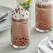 Two glasses of Fanale chocolate milkshakes with whipped cream and sprinkles on a table.