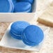 A white plate of blue macarons with white filling.