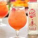 A glass of Master of Mixes Almond Syrup mixed with orange juice and ice with a cherry on top.