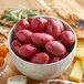 A white bowl filled with red Frutto d'Italia Cerignola olives.