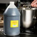 A person pouring Shank's Premium Pure Vanilla Extract into a silver bowl on a counter.