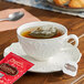 A white cup of Celestial Seasonings peppermint tea with a tea bag in it on a saucer.
