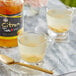 A glass of Assi ginger tea next to a jar of lemon juice.