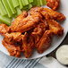 A plate of buffalo wings and celery sticks.