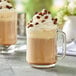 A glass mug of Capora coffee frappe mix with whipped cream and chocolate chips.