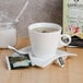 A cup of Bromley Exotic Passion Fruit Green Tea on a saucer with a tea bag next to a box of Bromley tea.