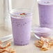 A purple drink made with Bossen Taro Powder in a plastic cup next to a bowl of chips.