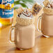 A glass mug of milkshake with Torani Sugar-Free S'mores Flavoring and marshmallows and whipped cream.