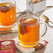 A wooden tray with two glass mugs of Twinings Spiced Apple Chai Tea with red tea bags in them.