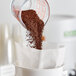 A measuring cup pouring brown Toddy Blend coffee into a bag.