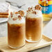 Two glasses of brown liquid flavored with Torani English Toffee syrup topped with whipped cream and nuts.