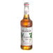 A Monin bottle of Macadamia Nut flavoring syrup with a white label.