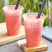 Two cups of Fanale strawberry drinks with straws on a wooden surface.