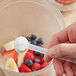 A hand holding a spoon of Add A Scoop Vitamin C Blend supplement powder.