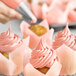 A close-up of a cupcake with pink frosting.
