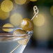 A green olive with Belosa Pepperjack cheese inside on a toothpick in a martini glass.