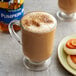 A glass mug of brown coffee next to a bottle of Torani Sugar-Free Pumpkin Pie Flavoring Syrup.