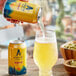 A hand pouring Athletic Brewing Co. Upside Dawn Non-Alcoholic Golden Ale from a yellow can into a glass.